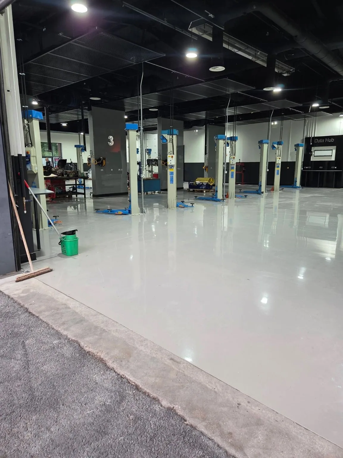 Clean grey workshop floor around vehicle lifts at Accrington College