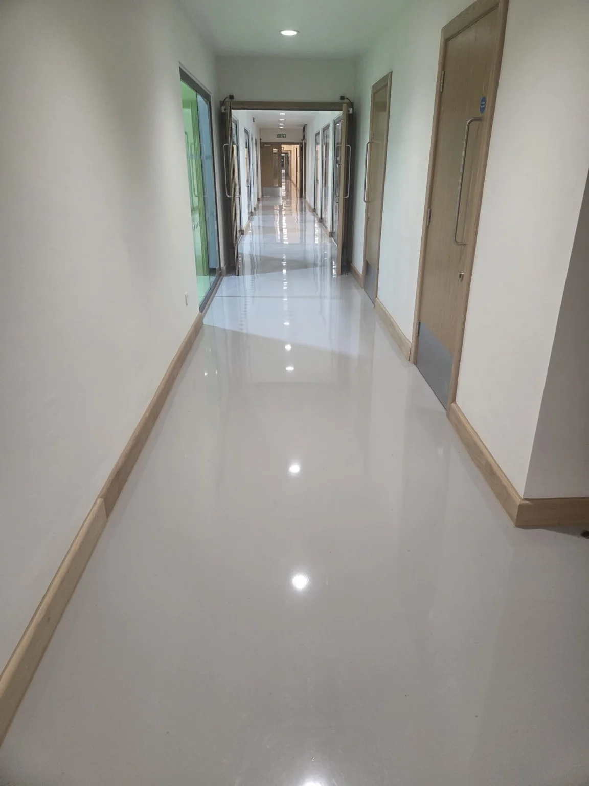 Clean communal corridor with light flooring and timber doors