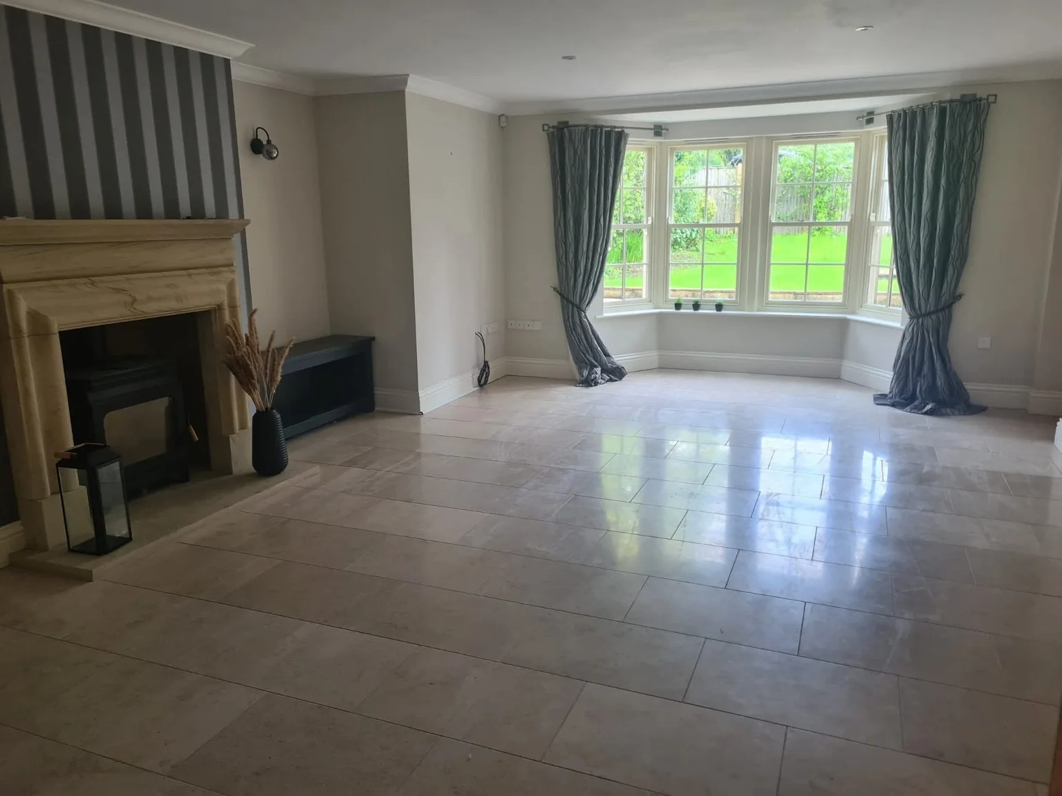 Clean empty living room with a fireplace, tiled floor and bay window