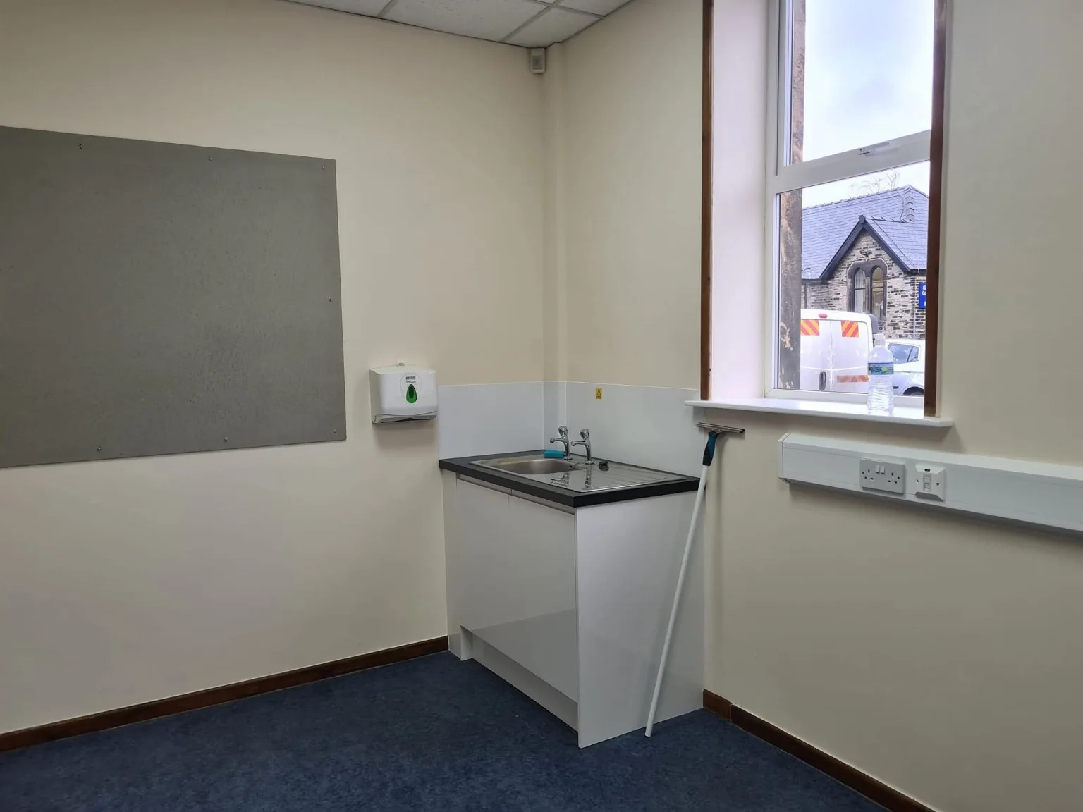 School room with blue carpet, a sink and cleaning equipment during opening preparations