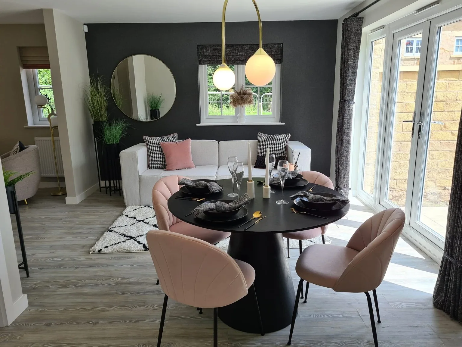 Show home dining table and living area beside glazed garden doors